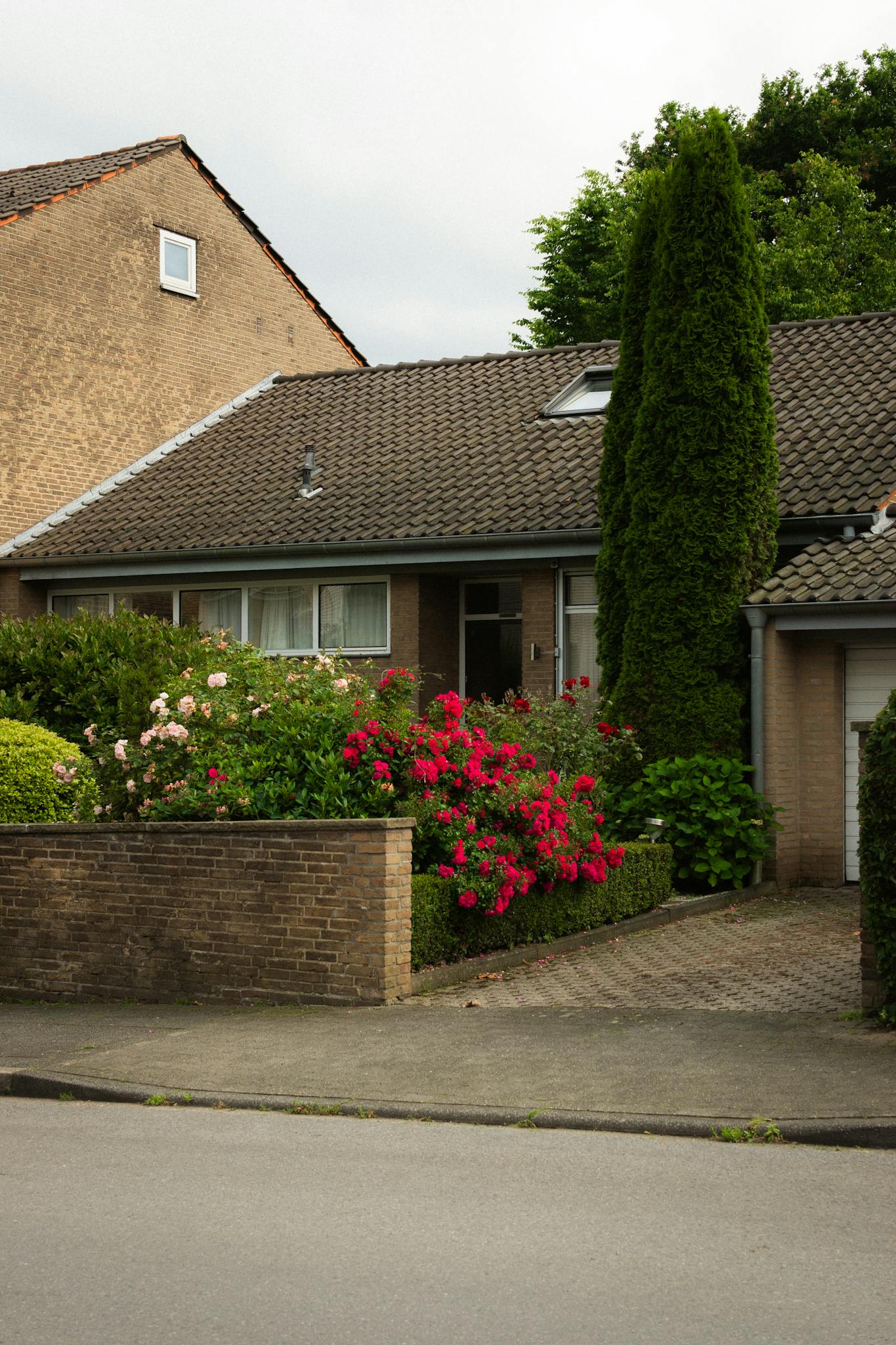 Cozy suburban brick house with vibrant garden and driveway.